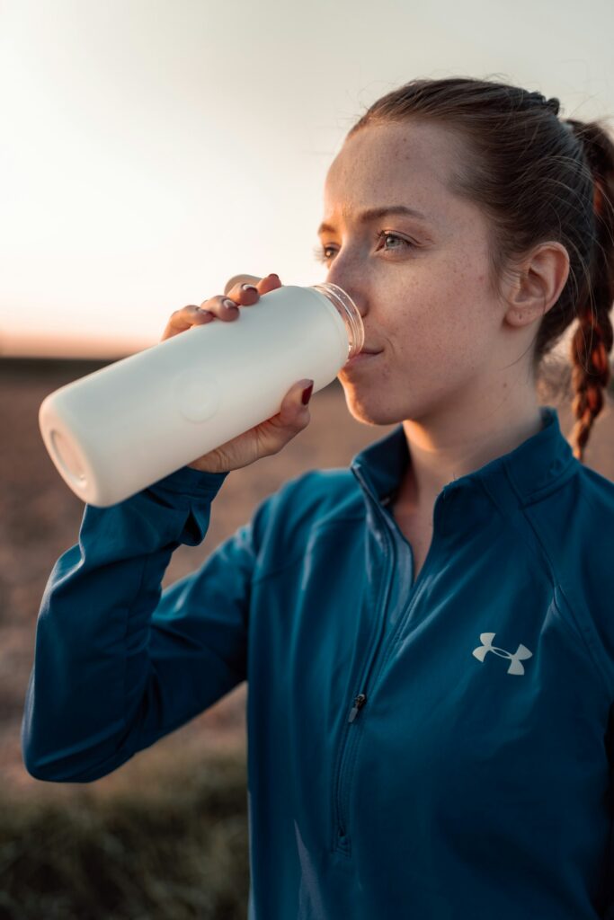 Sportlerin trinkt vor dem Lauf aus einer Trinkflasche
