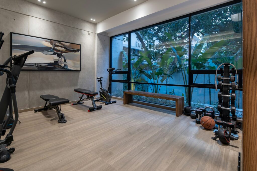 Home-Gym einrichten: heller Trainingsraum mit Hantelbank, Geräten und großen Fenstern