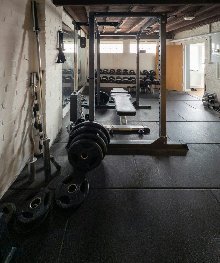 Heimtrainingsraum mit Rack, Hantelbank und Hantelscheiben auf Gummiboden