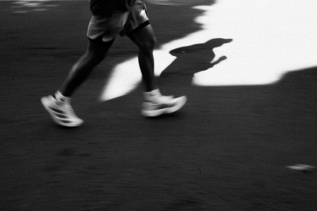Beine eines Läufers mit langem Schatten beim Intervalltraining Laufen