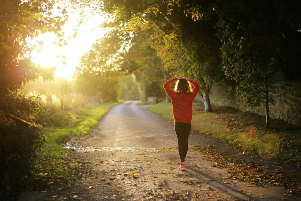 Frau geht zügig auf einem Weg – Gehpausen gehören zum Joggen lernen dazu