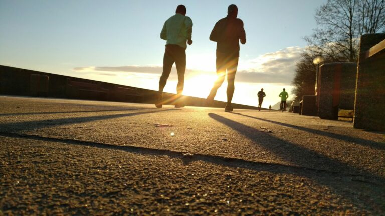 Zwei Männer joggen locker durch einen Park – Joggen lernen in entspanntem Tempo