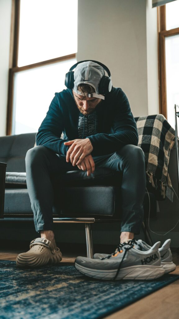 Mann sitzt auf der Couch neben seinen Sportschuhen – keine Lust auf Sport nach einem langen Tag