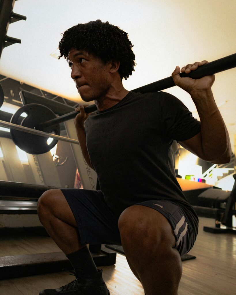 Mann in tiefer Kniebeuge mit Langhantel im Fitnessstudio