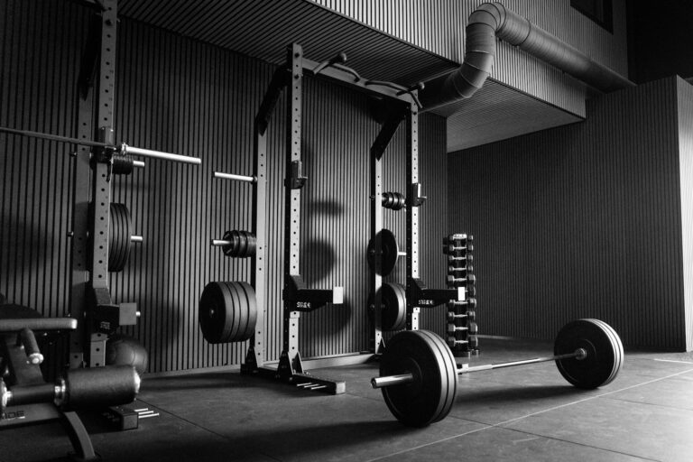 Kniebeugen-Rack als Power-Rack mit Langhanteln und Gewichten in einem leeren Trainingsraum
