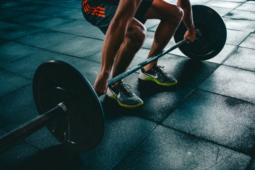 Progressive Overload: Person greift die Langhantel zum schweren Heben