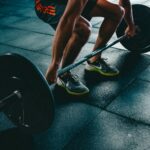 Progressive Overload: Person greift die Langhantel zum schweren Heben