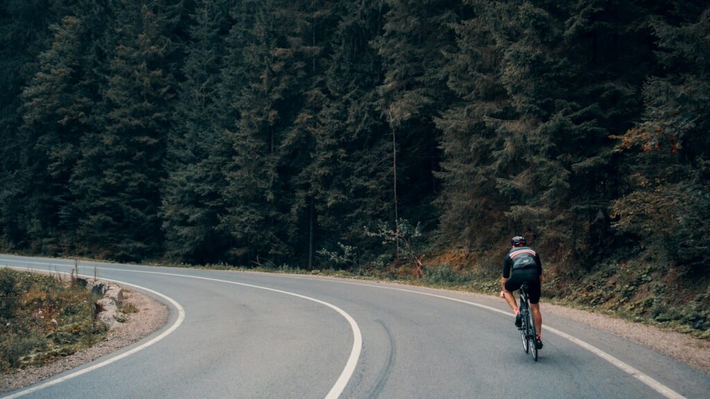 Radfahrer auf einer Waldstraße: Mit Muskelkater Sport machen gelingt am besten locker