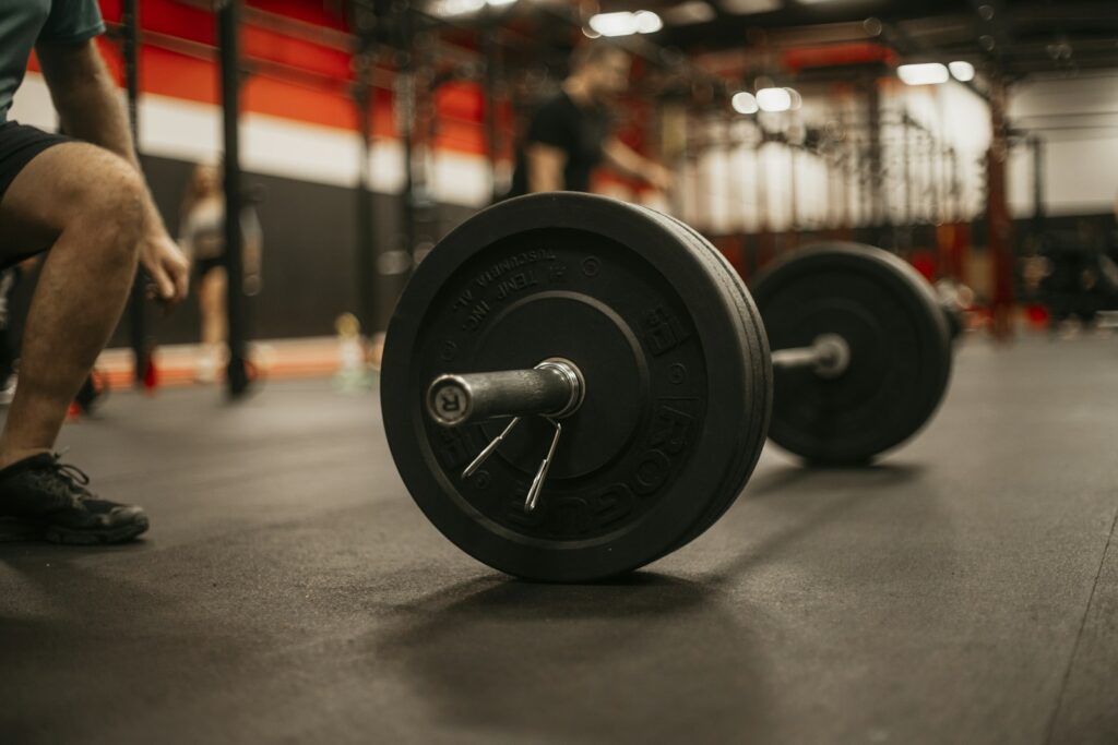 Mann hockt vor dem Satz neben der Langhantel im Gym