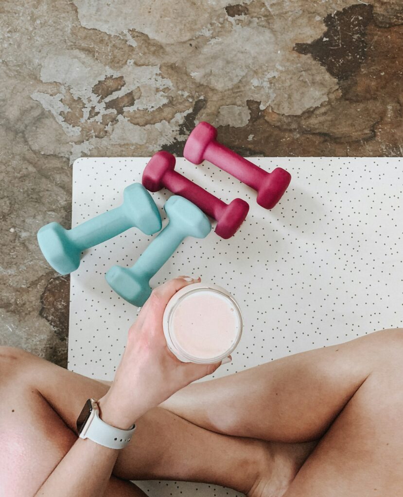 Becher mit Proteinshake über zwei Paar Kurzhanteln, Protein Shake wann nehmen rund ums Training