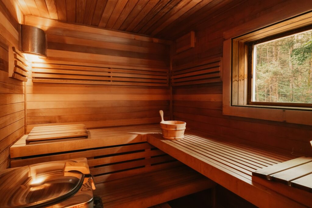 Holzsauna mit Bänken, Kübel und Blick in den Wald