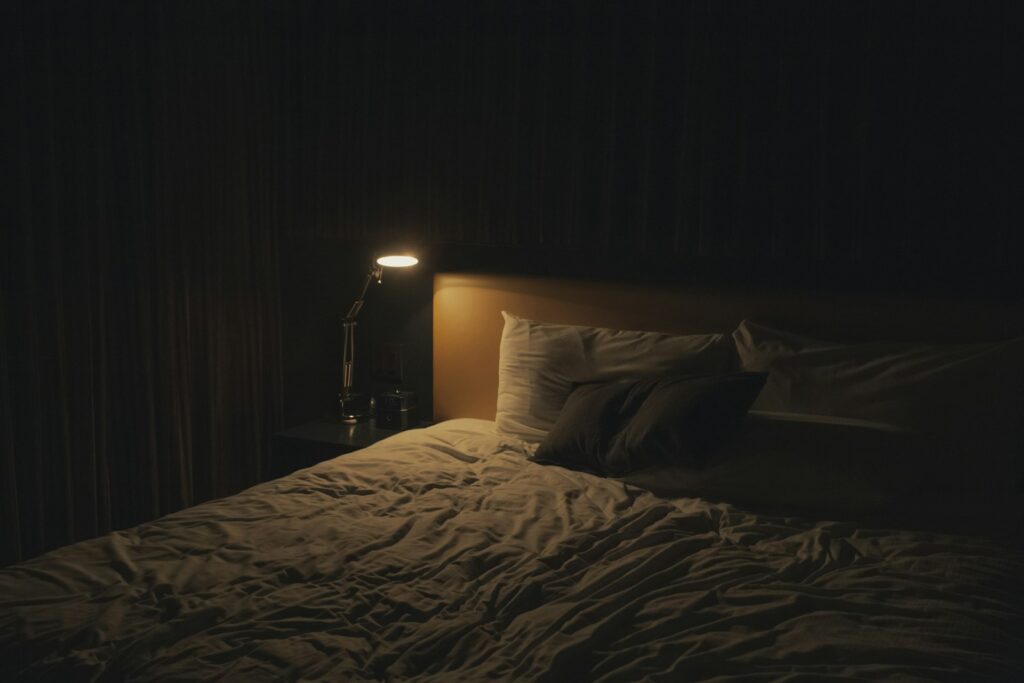 Gedimmte Nachttischlampe neben dem Bett als Teil einer ruhigen Abendroutine