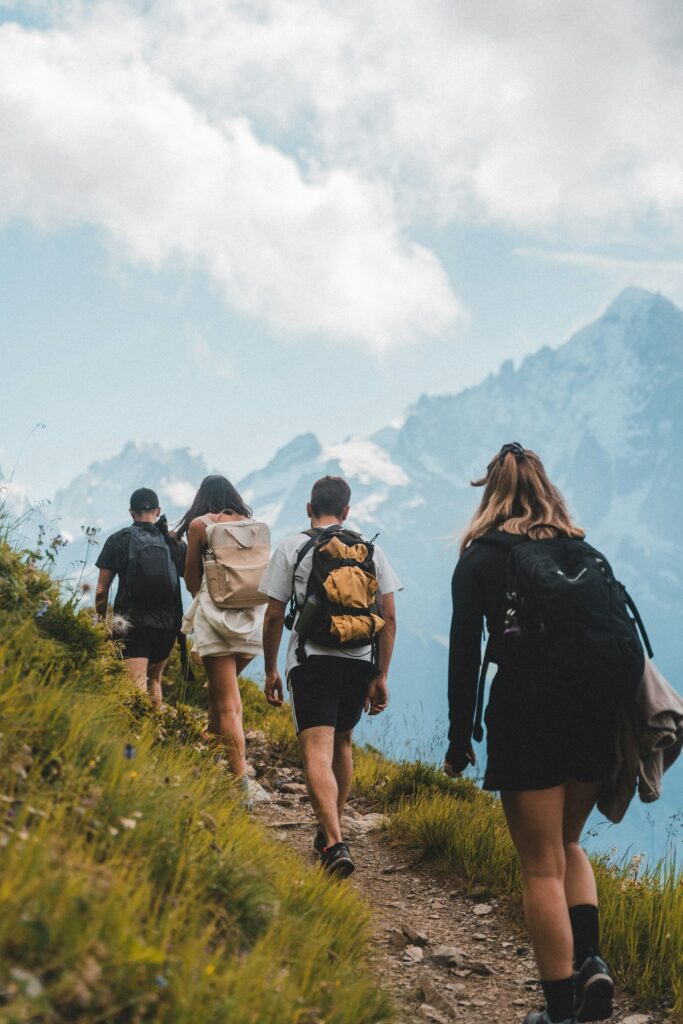 Vier Wandernde mit Rucksäcken auf einem Bergpfad – gemeinsame Bewegung stärkt Sport und Psyche