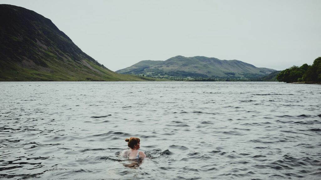 Frau schwimmt in einem Bergsee mit Bergen im Hintergrund