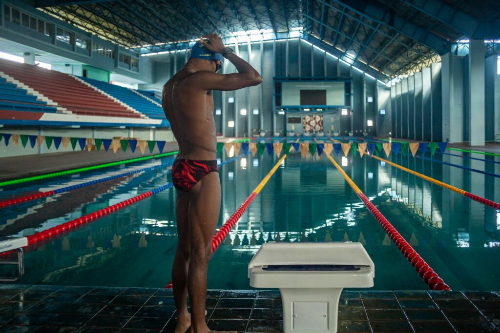 Schwimmer richtet am Beckenrand seine Badekappe und konzentriert sich – Visualisierung im Sport vor dem Start