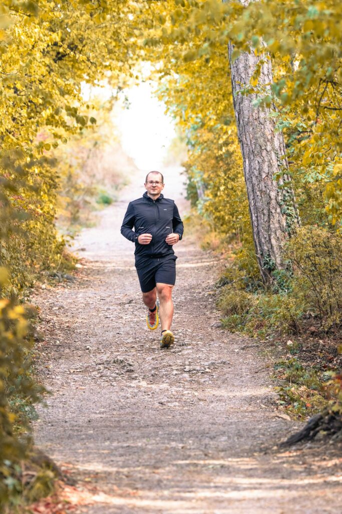 Läufer auf einem Waldweg im Herbst beim lockeren Dauerlauf